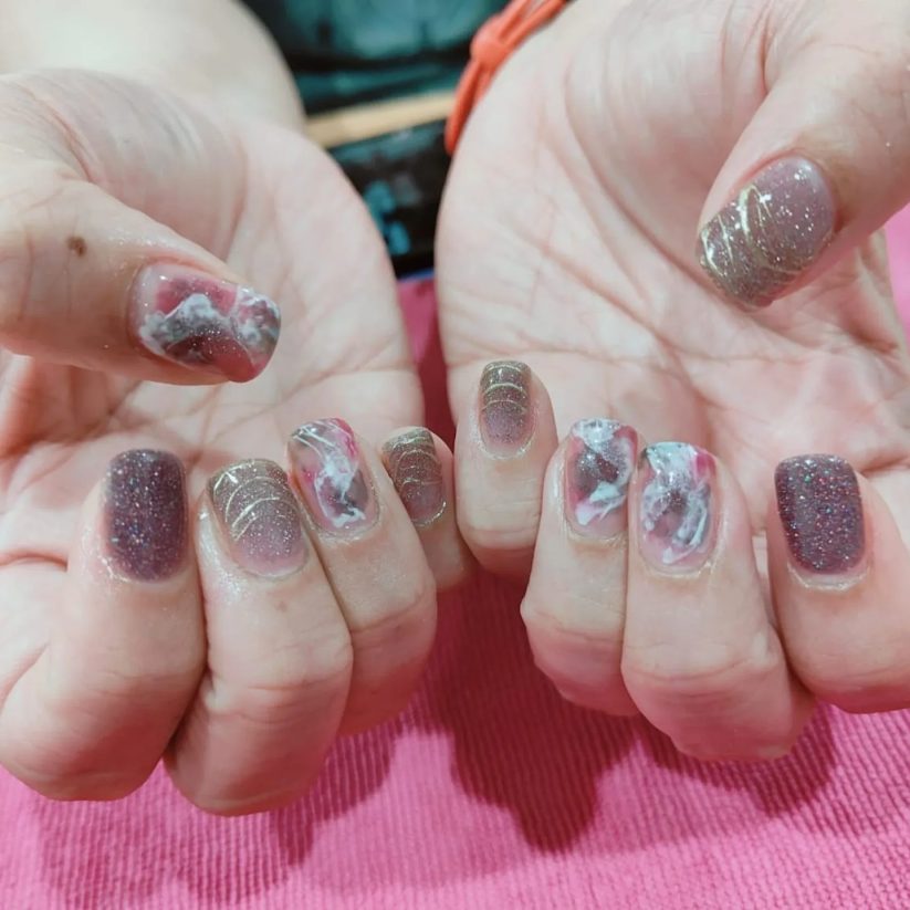 Two hands with blue marble and glitter nail art